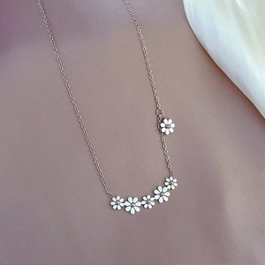 Close-up of silver titanium steel necklace featuring six delicate daisy flower pendants