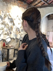Detail of a vintage black bow hair clip styled on a braid with a metallic earring