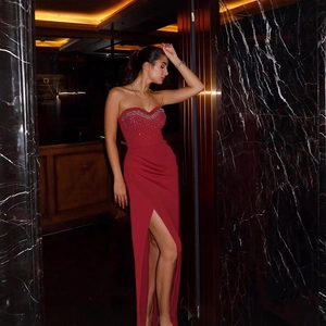 Elegant red strapless evening gown with rhinestones and high slit in luxury setting