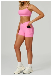 Close-up of pink high-waisted fitness shorts showing functional side pocket with camera