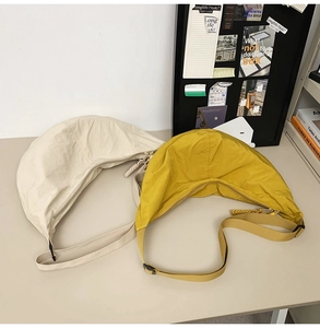 Sacs croissants en nylon beige et jaune avec bandoulières réglables sur un bureau