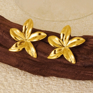 Détail des boucles d'oreilles fleur plaquées or 18 carats sur support en bois