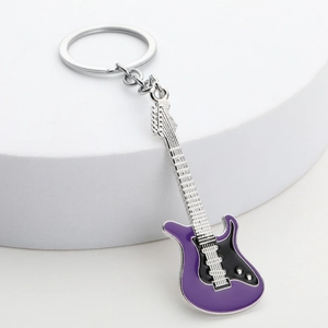 Detail shot of purple and black enamel guitar keychain on a white pedestal display