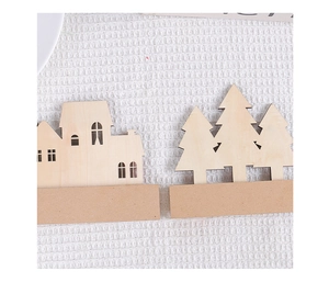 Flat lay detail of natural wood house and tree ornaments on white knit texture
