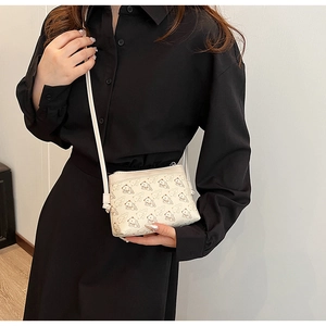 Détail d'un sac bandoulière en cuir PU crème avec motif ours porté par un mannequin