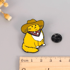 Detailed view of a cowboy cat enamel pin next to a ruler showing its 3-4cm size dimensions