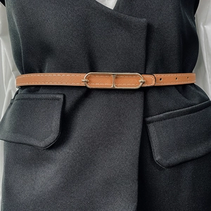 Detail of slim brown leather belt with gold geometric buckle on a black vest