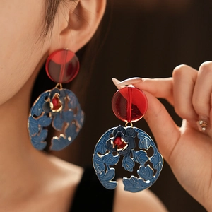 Detail view of vintage style gold-rimmed blue flower earrings worn by a model