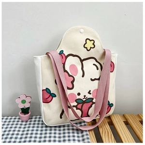 Close-up of beige canvas tote bag with cute rabbit and peach print and pink handles