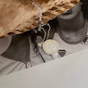 Sterling silver necklace featuring a round angel shell relief pendant on a minimalist chain