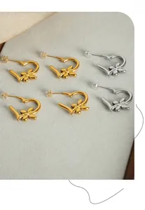 Detail of heart-shaped gold and silver earrings featuring small floral accents