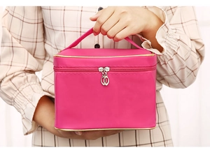Close-up of rose red satin makeup bag with gold trim and dual zipper top handle