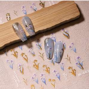 Macro shot of 5D lily floral nail decals with gold foil accents and 3D embossed texture