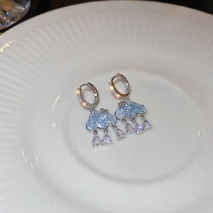 Détail de boucles d'oreilles nuage bleu avec zircons gouttes sur une assiette
