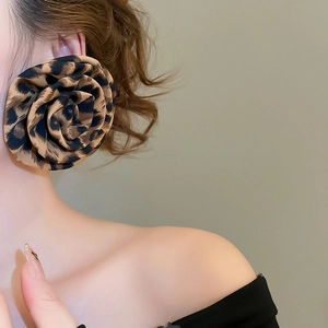 Close-up of leopard print fabric flower earrings worn by a model in a soft lighting