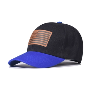 Detail of the American flag leather patch on a two-tone black and blue baseball cap