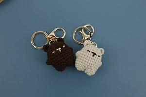 Detail of brown and beige hand-knitted bear keychains with gold metal lobster clasps