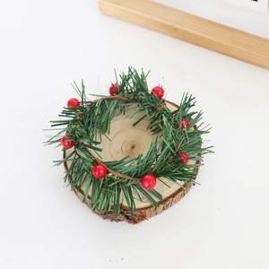 Close-up of Christmas mini wreath with green pine needles and red holly berries on wood base