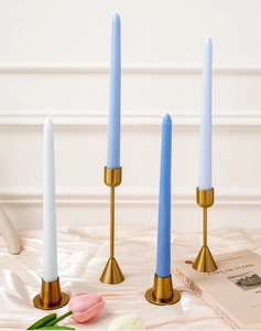 Portavelas de metal dorado con velas cónicas azul claro y blancas sobre seda rosa