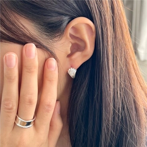 Close-up of minimalist sterling silver shell earrings and layered ring on female model