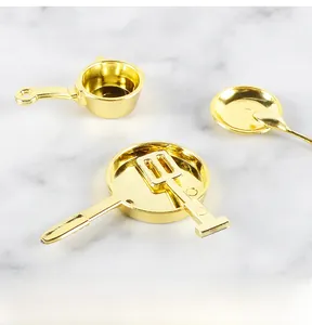 Detailed macro view of gold miniature kitchenware set including pans and spatulas