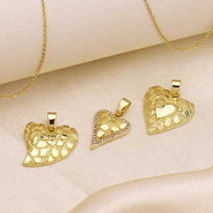Three textured 18k gold heart pendants on silk fabric with a delicate gold chain