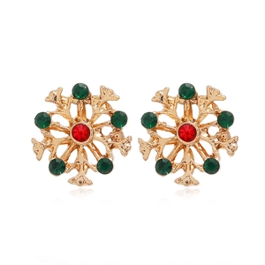 Détail de boucles d'oreilles flocon en or avec strass rouges et verts brillants