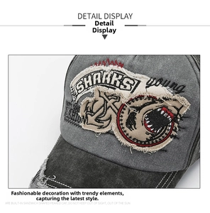 Detail of vintage washed grey cotton baseball cap with embroidered anchor and shark patches