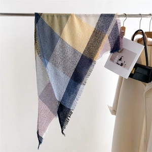 Detailed view of soft cashmere-feel scarf with blue and yellow plaid pattern and tassels