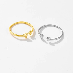 Detailed view of two heart-shaped S925 silver rings in gold and silver finish