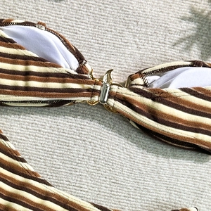 Detail of striped bikini featuring textured coffee and beige fabric with gold metal clasp