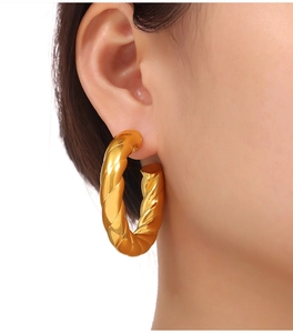 Close-up of chunky gold croissant hoop earrings with textured twisted rope finish