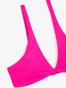 Dettaglio del top bikini magenta con profondo scollo a V e nodo a torsione sul davanti