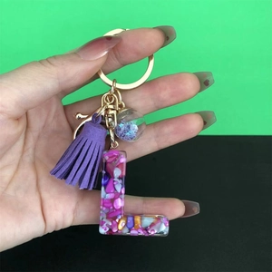 Close-up of Letter L resin keychain with purple tassel and colorful stones