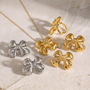 Flat lay of 18k gold and silver bow jewelry set including necklace, earrings and ring