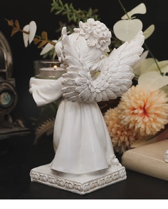 Detail of white resin angel candle holder showing intricate feather textures and flower