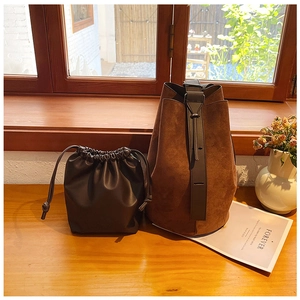 Deep brown suede bucket bag set with inner drawstring pouch on a wooden windowsill
