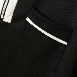 Detail of black polo shirt featuring white contrast piping on pocket and metal zipper
