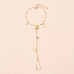Detailed macro view of a gold-tone finger bracelet with butterfly and star charms