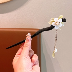 Detailed shot of sandalwood hair stick featuring white jade flowers and metallic tassels