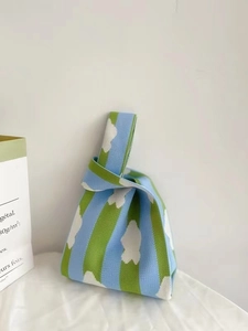 Detailed close-up of blue and green striped knitted tote bag with white cloud patterns