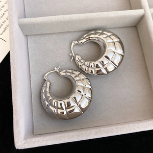 Close-up of silver chunky hoop earrings with quilted texture in a velvet jewelry box