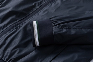 Macro detail of navy blue lightweight jacket cuff with white and green stripe ribbing