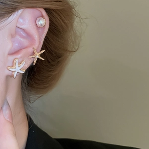Detail view of starfish stud earrings set with pearls on ear for beach vacation look