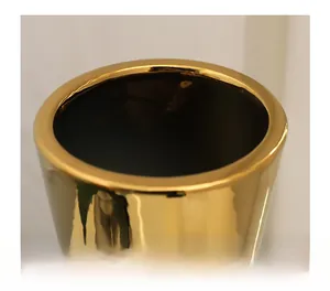 Close-up of a modern gold ceramic vase with a polished mirror finish and wide round rim