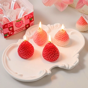 Realistic strawberry shaped scented candles in red and pink on white ceramic plate