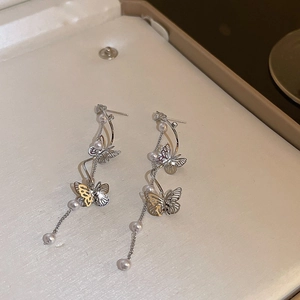 Detail shot of silver butterfly earrings with long pearl tassels and crystal accents