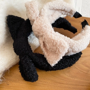 Close-up of fluffy bow headbands in black and beige with warm wood background