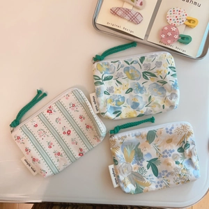 Three green floral cotton mini pouches with zippers and woven labels on white background