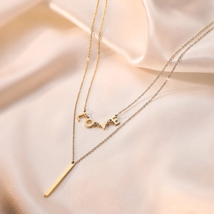 Minimalistische doppellagige vergoldete Halskette mit LOVE-Anhänger auf beiger Seide